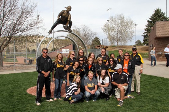 The softball team poses in front of the sculpture
