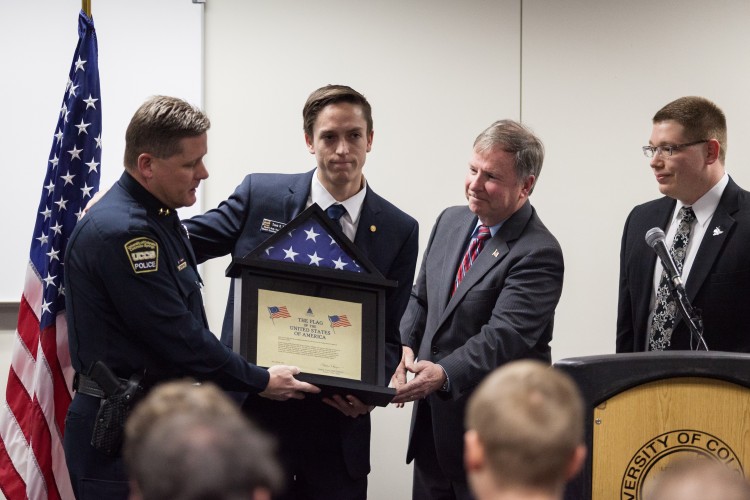 UCCS Police Chief Brian McPike, left, receives a U.S. flag from Rep. Doug Lamborn, R-Colorado, while Travis Trafoya student, and Aaron Novy, Business 2011, look on.
