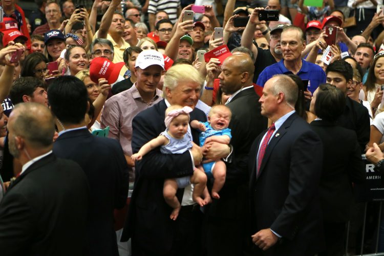 Republican presidential candidate Donald Trump carries babies during a July 29 campus event.