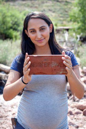 Anna holds up an old red brick with lettering embossed