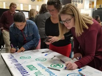 Conference attendees sign a banner in the Gallogly Events Center.