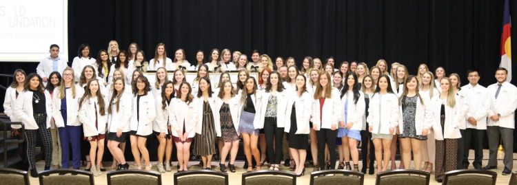 Group of nursing students pose with their white coats in Berger Hall.