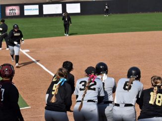 A softball student-athlete jogs to home plate where her teammates are gathered.