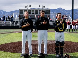 Three baseball student-athletes stand at the pitchers mound for the National Anthem