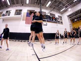 Two women's basketball student-athletes meet at the free throw line during pregame introductions.