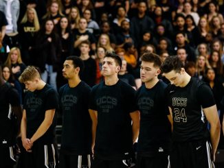 Men's basketball student-athletes stand for pregame introductions at Blackout Night 2019