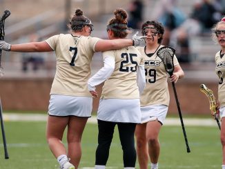 The women's lacrosse team celebrates on the field.