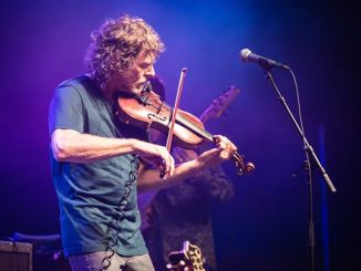 Sam Bush plays the fiddle on a stage