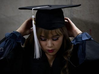 A graduate adjusts her cap before commencement