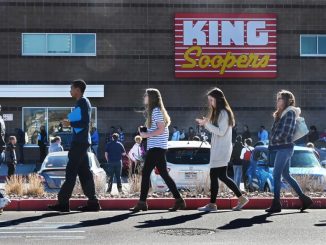 People line up in front of a King Soopers grocery store.