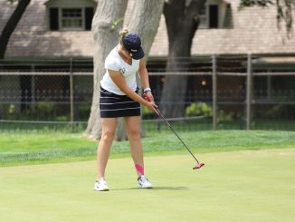 A women's golfer hits a putt on the green.