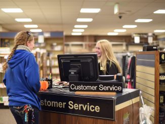 A student works at a customer service desk in the bookstore.