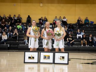 The three women's basketball seniors pose for a group photo at center court.