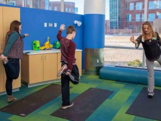 Three people conduct stretches in an activity room.
