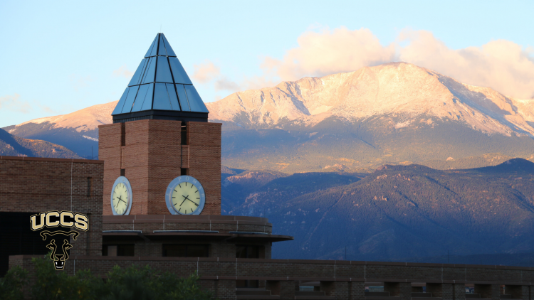 An early sunrise on campus with the El Pomar Center clock tower and Pikes Peak in the background
