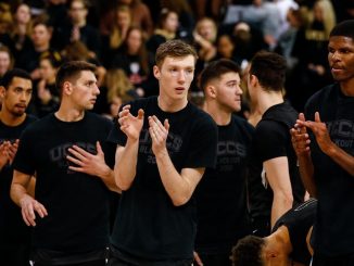 Members of the men's basketball team clap before the game starts