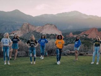 A group of volleyball student-athletes stand in front of Pikes Peak