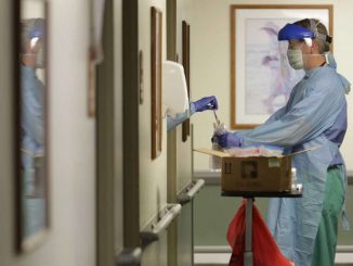 A doctor is handed a swab in a hospital hallway