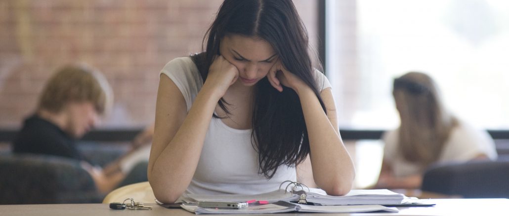 A student rests their head on their hands in the library