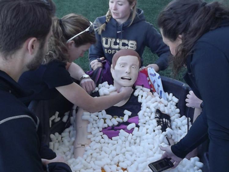 Students working with a mannequin during an athletic training class