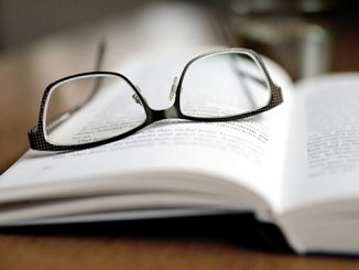 A pair of glasses laying on an open book page