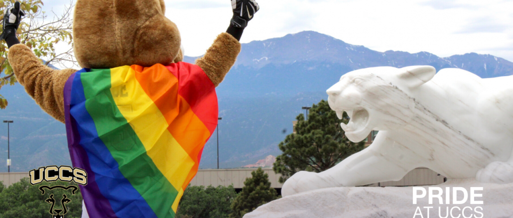 Clyde with a rainbow flag standing next to the Mountain Lion statue