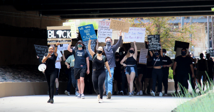 Peeople marching under a bridge while holding signs