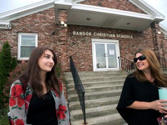 Two people stand outside a school in Maine