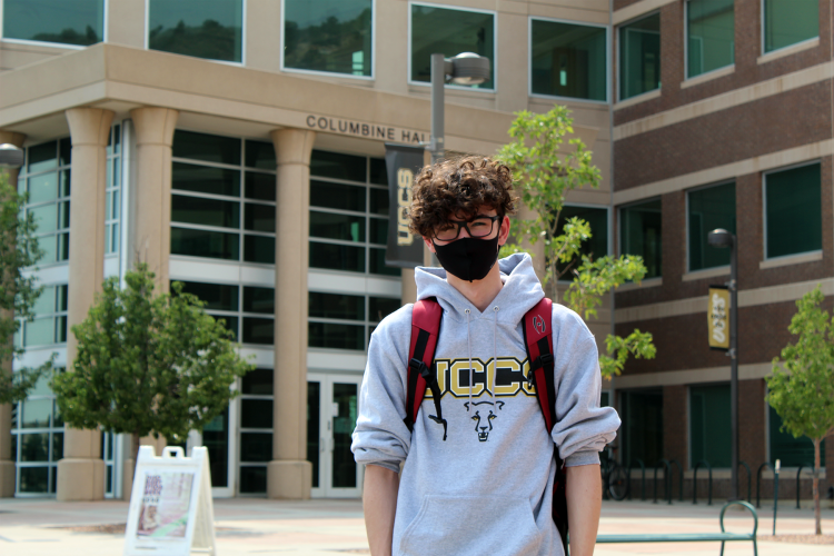 Student wearing a mask standing in front of building