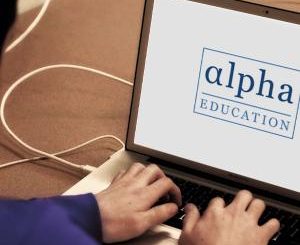 An open laptop with the Alpha Education logo on the screen