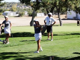 A women's golfer hits the ball from the tee box