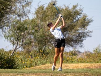 A golfer hits a ball from the tee box