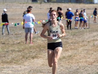 A women's cross country runner nearing the finish line of a race