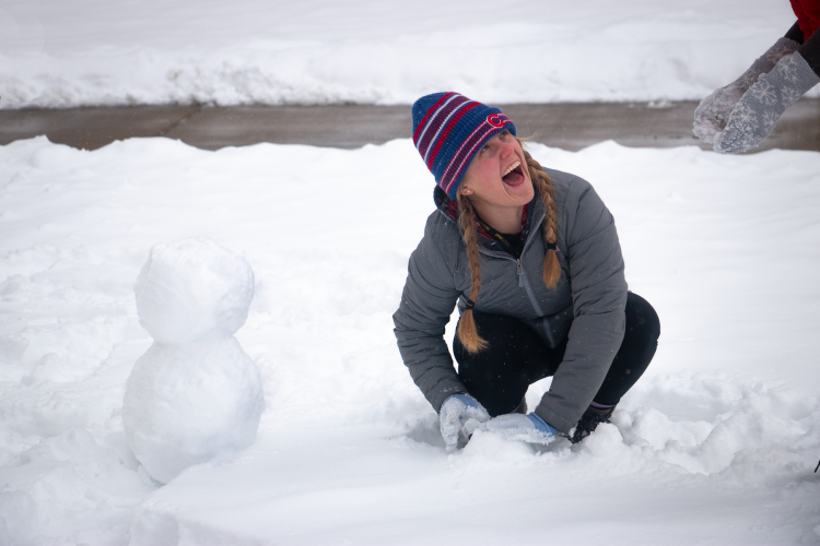 A student builds a snowman outside of Roaring Fork dining hall.