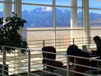 A student studying in Dwire Hall with Pikes Peak through the windows