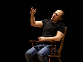 Jonathan Marcantoni performing a monologue from a chair