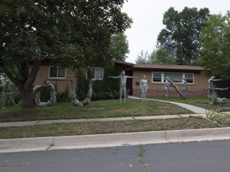 Sculpture of life-size human beings spelling Routine in a front yard