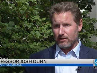 Josh Dunn conducting an interview in front of a tree