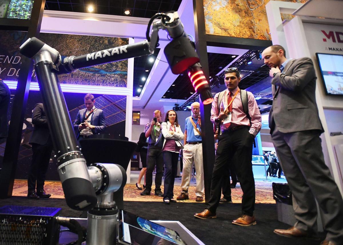 Two people look at a robot during the 2019 Space Symposium