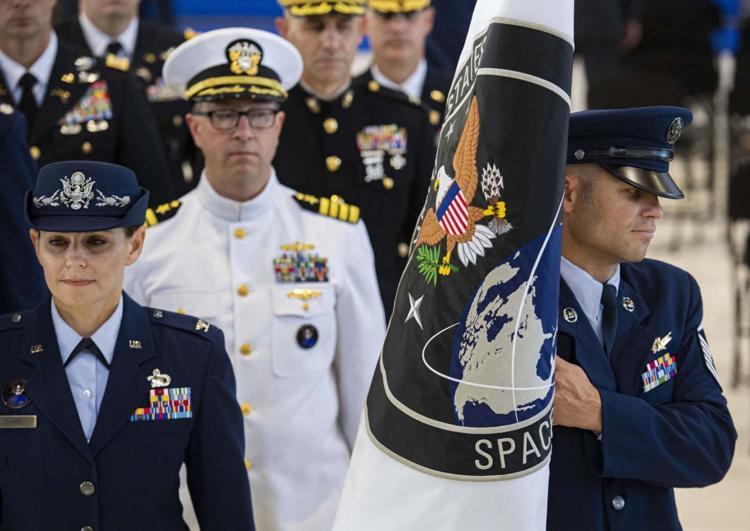 Air Force officers walking, with one holding a flag for United States Space Command