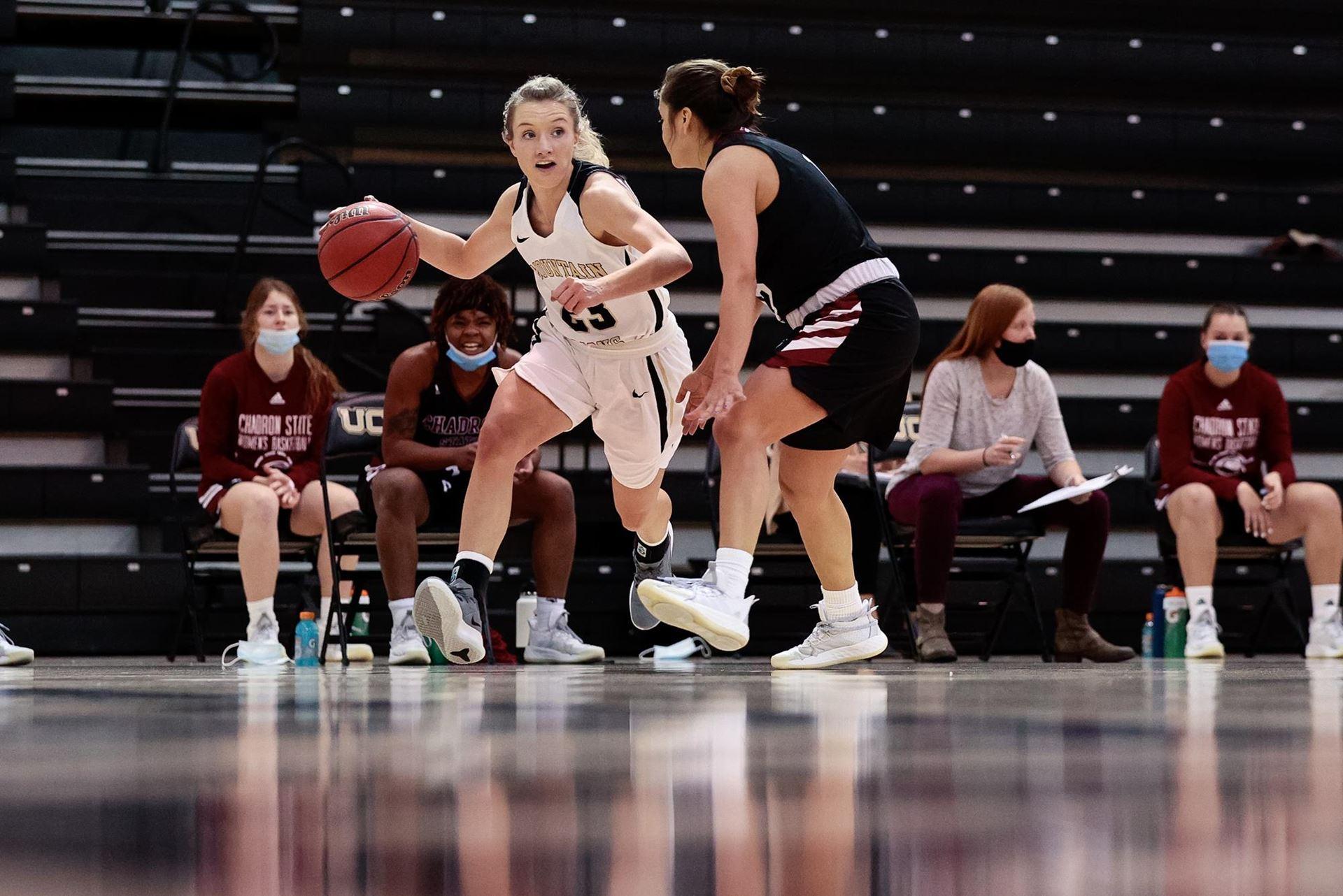 Abby Feickert dribbling the basketball against a Chadron State defender