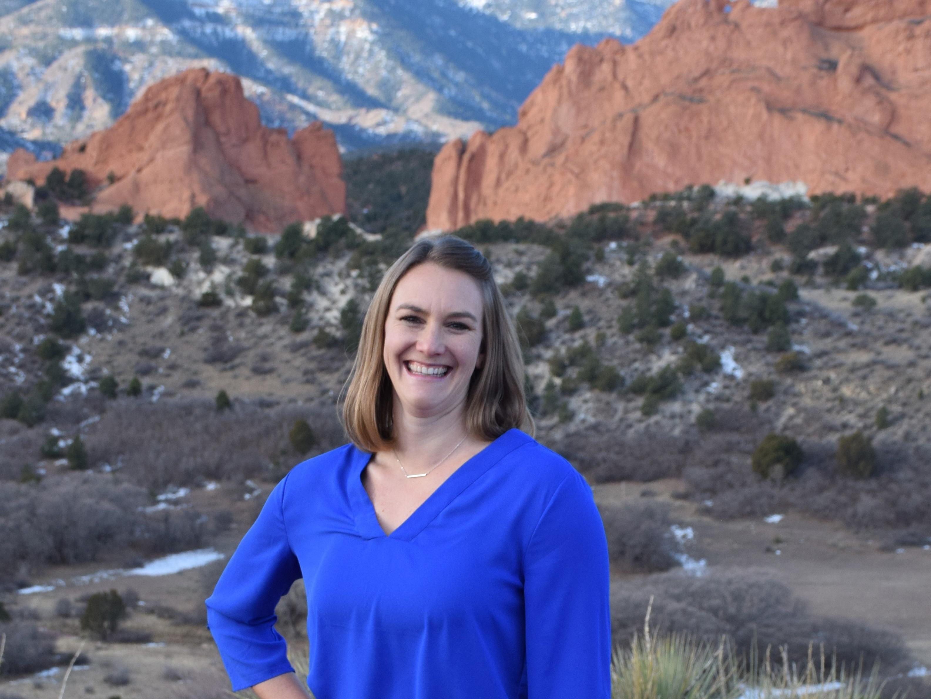 Jennifer Best smiles in a headshot photo with garden of the gods behind her