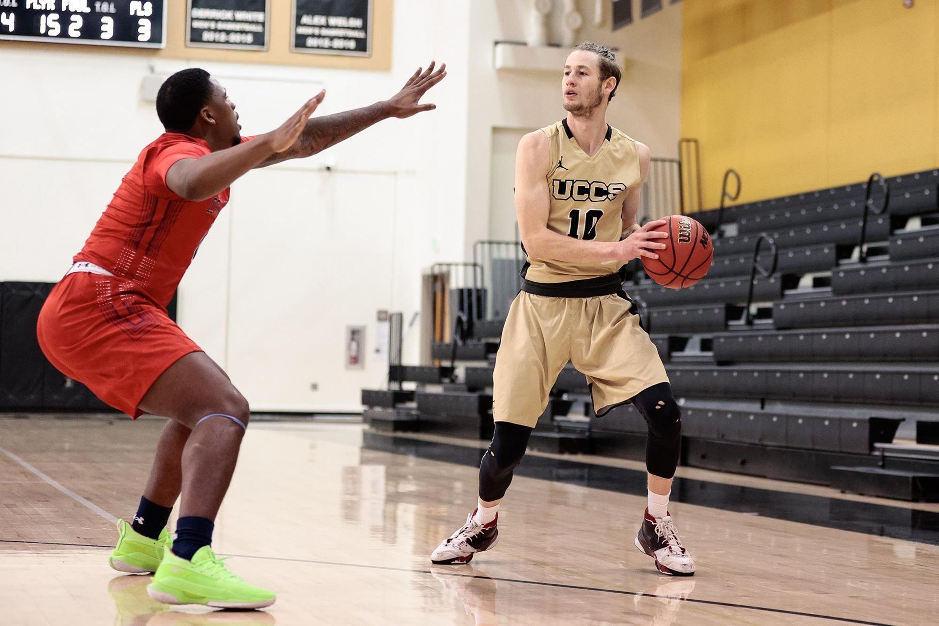 Cam Underwood holding a basketball against a defender in Gallogly Events Center