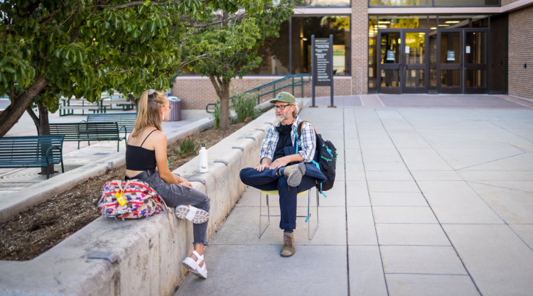 A student and a staff member talk outside of the University Center.