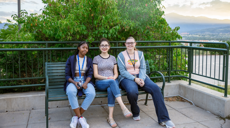 Three students hang out on a bench.